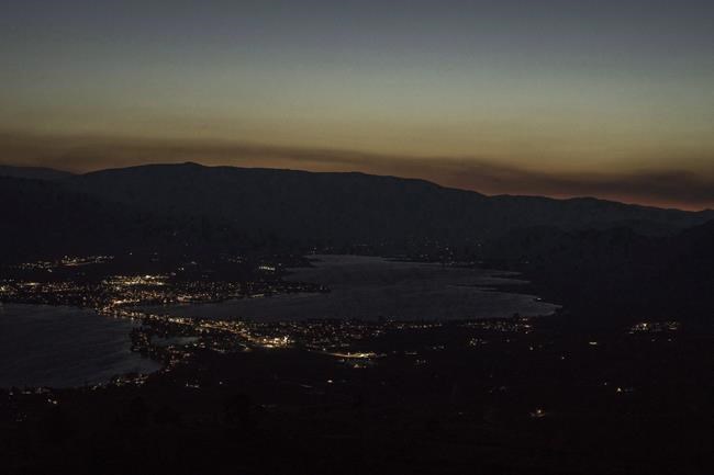 Looking high above the small town of Osoyoos B.C. in the southern Okanagan the glow of smoke and fire illuminates the night sky on Thursday July 19, 2018. At least 160 properties have been ordered to evacuate as an aggressive wildfire burns in the south Okanagan. THE CANADIAN PRESS/Jeff Bassett