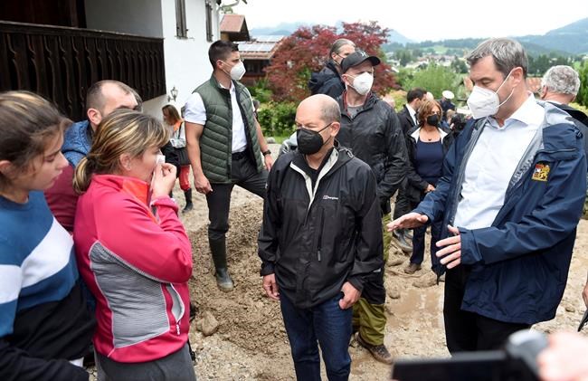 FILE - In this July 18, 2021 file photo Markus Soeder, right, chairman of the CSU and Bavarian minister-president, and Olaf Scholz, center, federal finance minister and candidate for chancellor, talk with residents affected by flooding in Schoenau, Germany. (Felix Hoerhager/dpa via AP)