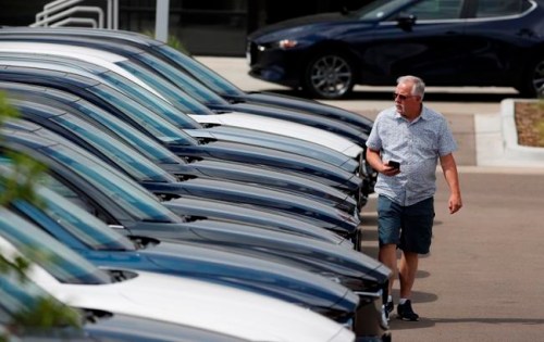 In this Sunday, June 14, 2020, photograph, a prospective buyer looks over a long row of unsold 2020 CX-5 sports-utility vehicles sedans sits at a Mazda dealership in Littleton, Colo. With car prices at record highs and inventory getting thinner, shoppers might be tempted to rush through a deal this summer without giving it much thought.  (AP Photo/David Zalubowski)