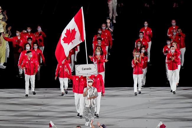 Team Canada flag-bearers Miranda Ayim and Nathan Hirayama carry the Canadian flag at the opening ceremonies during the Tokyo Olympics in Tokyo, Japan on Friday, July 23, 2021. THE CANADIAN PRESS/Adrian Wyld