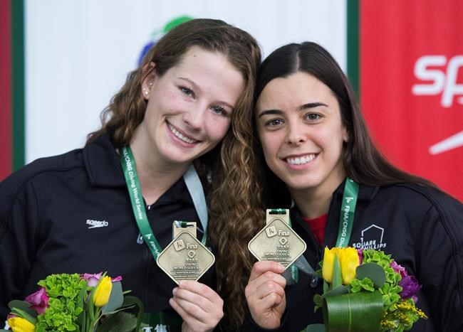 Meaghan Benfeito, right, and Caeli McKay of Canada hold up their gold medals after winning the women's 10-metre platform synchro final at the FINA Diving World Series in Montreal, Friday, February 28, 2020. THE CANADIAN PRESS/Graham Hughes