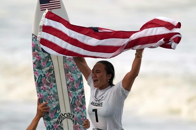 Carissa Moore, of the United States, celebrates winning the gold medal of the women's surfing competition at the 2020 Summer Olympics, Tuesday, July 27, 2021, at Tsurigasaki beach in Ichinomiya, Japan. (AP Photo/Francisco Seco)