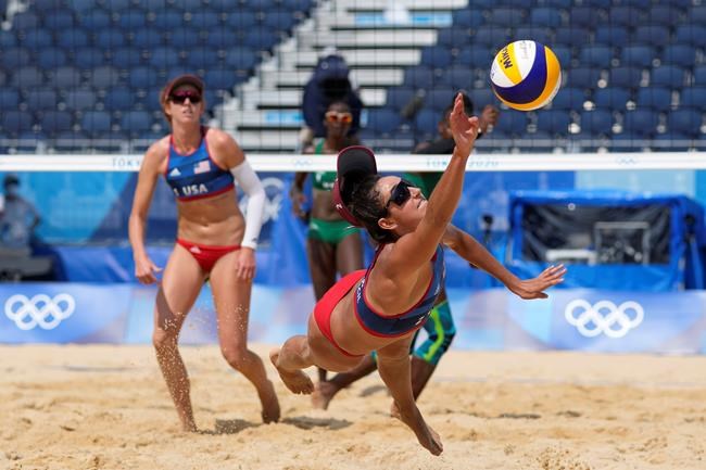 Sarah Sponcil, right, of the United States, stretches out for the ball as teammate Kelly Claes looks on during a women's beach volleyball match against Kenya at the 2020 Summer Olympics, Thursday, July 29, 2021, in Tokyo, Japan. (AP Photo/Petros Giannakouris)