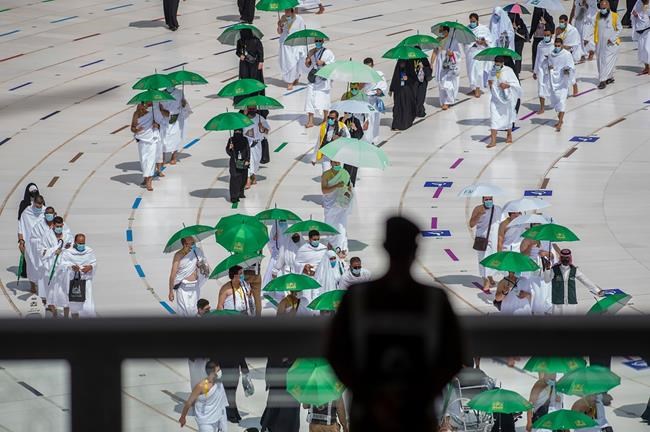 A Saudi security officer watches as Muslim hajj pilgrims, wearing masks and keeping social distancing to help prevent the spread of the coronavirus, circumambulate the Kaaba, a square stone structure in the Great Mosque, in Mecca Saudi Arabia, Tuesday, July 20, 2021. Once drawing some 2.5 million Muslims from across the globe to the holy city of Mecca, the Islamic pilgrimage has been dramatically scaled back due to the virus. (Saudi Media Ministry via AP)