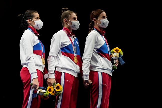Hand by hand, gold medalists Russian Olympic committee Sabre team listen to the Russian Olympic Committee anthem during the medal ceremony for the women's Sabre team final medal competition at the 2020 Summer Olympics, Saturday, July 31, 2021, in Chiba, Japan. (AP Photo/Hassan Ammar)
