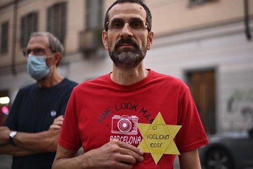 FILE - In this Wednesday, July 28, 2021 file photo, a man shows a sign shaped like a Star of David reading in Italian 