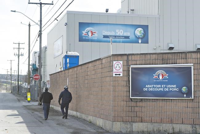 Workers walk outside the Olymel pork-processing plant in Vallee-Jonction, Que., Thursday, Oct. 29, 2020. Quebec pork producers are asking the government to intervene and end the ongoing labour strike at the Olymel slaughterhouse in Vallée-Jonction, south of Quebec City. THE CANADIAN PRESS/Jacques Boissinot