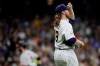 Milwaukee Brewers' Corbin Burnes, foreground, adjusts his cap as San Francisco Giants' Brandon Belt rounds third base after hitting a solo home run during the sixth inning of a baseball game Friday, Aug. 6, 2021, in Milwaukee. (AP Photo/Aaron Gash)