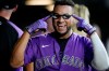 Colorado Rockies' Elias Diaz points to the home run shades he donned after returning to the dugout following his solo home run off Miami Marlins relief pitcher Steven Okert in the fourth fifth inning of a baseball game Friday, Aug. 6, 2021, in Denver. (AP Photo/David Zalubowski)