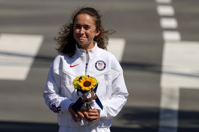Molly Seidel, of United States, stands on the podium for a flower ceremony following her third place finish in the women's marathon at the 2020 Summer Olympics, Saturday, Aug. 7, 2021, in Sapporo, Japan. (AP Photo/Shuji Kajiyama)