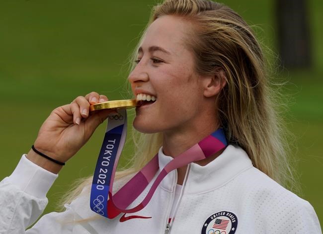 Nelly Korda, of the United States, bites her gold medal, won in the women's golf event at the 2020 Summer Olympics, Saturday, Aug. 7, 2021, at the Kasumigaseki Country Club in Kawagoe, Japan. (AP Photo/Matt York)