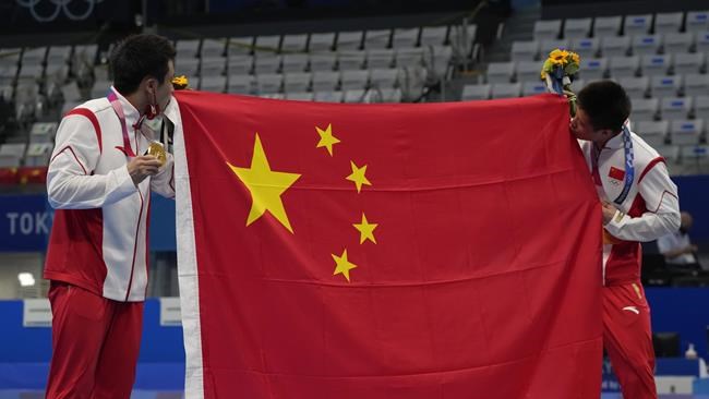 Cao Yuan of China, left, gold medal and Yang Jian of China, silver medal kiss their flag after men's diving 10m platform final at the Tokyo Aquatics Centre at the 2020 Summer Olympics, Saturday, Aug. 7, 2021, in Tokyo, Japan. (AP Photo/Dmitri Lovetsky)