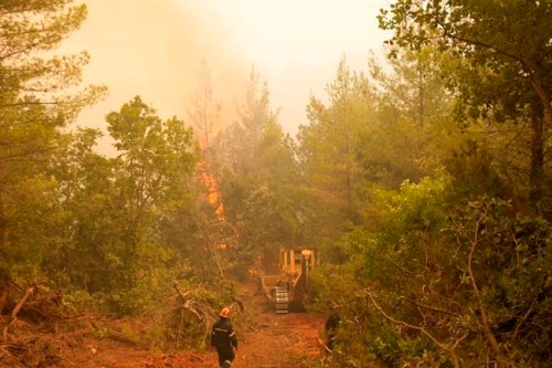 A bulldozer opens fire break during a wildfire at Kamaria village on Evia island, about 189 kilometers (114 miles) north of Athens, Greece, Tuesday, Aug. 10, 2021. Firefighters and residents battled for an eighth day against a massive fire on Greece's second-largest island as the nation endured what the prime minister described as 