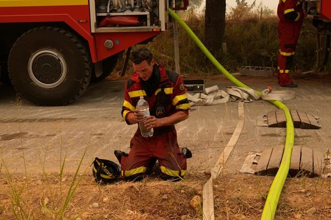 A firefighter from Slovakia cools himself down during a wildfire in Avgaria village on Evia island, about 184 kilometers (115 miles) north of Athens, Greece, Tuesday, Aug. 10, 2021. A massive wildfire burning for days on the northern tip of Greece's second largest island Tuesday continues to devour forests, its thick smoke hanging in the streets of a nearby town as hundreds of firefighters battled to save what they could. (AP Photo/Petros Karadjias)