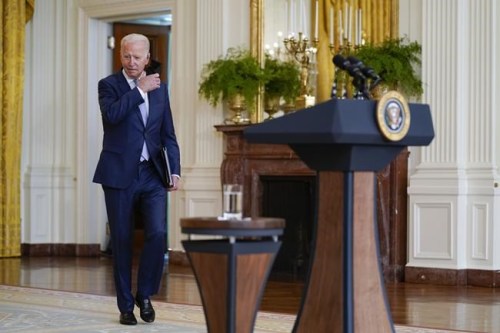 President Joe Biden removes his face mask as he arrives to speak about prescription drug prices and his 
