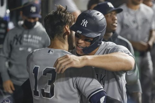 New York Yankees' Joey Gallo, left, gets a hug in the dugout from Aaron Judge after Gallo's two-run home run off Chicago White Sox relief pitcher Liam Hendriks during the 10th inning of a baseball game, Saturday, Aug. 14, 2021, in Chicago. (AP Photo/Kamil Krzaczynski)