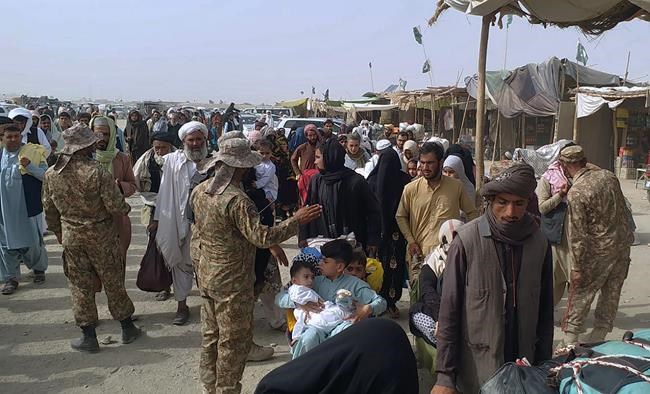 Pakistan soldiers check documents of travelers crossing the border to Afghanistan through a crossing point in Chaman, Pakistan, Monday, Aug. 16, 2021. A special flight of Pakistan’s national airline PIA has arrived in Islamabad carrying 329 passengers from Kabul, and another carrying 170 people will arrive later today. A spokesman for the airline said Saturday that the airline will operate three flights tomorrow to transport Pakistanis and other nationalities looking to leave Kabul. (AP Photo/Jafar Khan)
