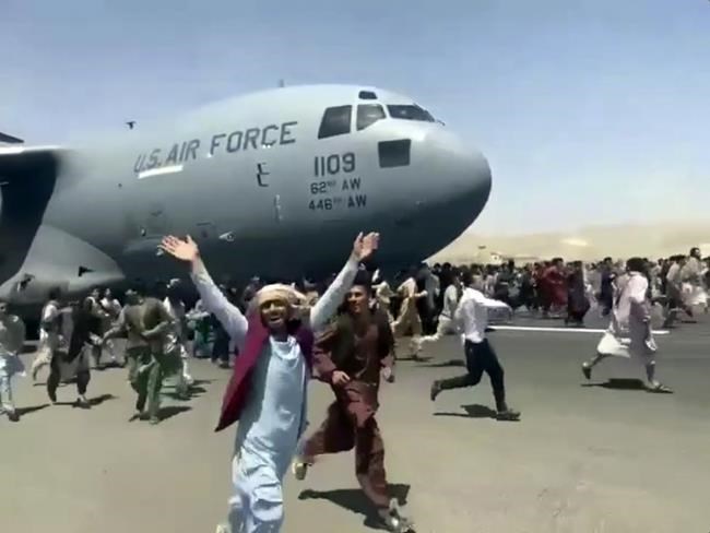 Hundreds of people run alongside a U.S. Air Force C-17 transport plane as it moves down a runway of the international airport, in Kabul, Afghanistan, Monday, Aug.16. 2021. Thousands of Afghans have rushed onto the tarmac of Kabul’s international airport, some so desperate to escape the Taliban capture of their country that they held onto an American military jet as it took off and plunged to death. (Verified UGC via AP)