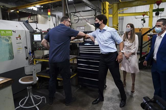 Liberal Leader Justin Trudeau gives an employee an elbow bump as he and Liberal candidate for the riding of Longueuil-Saint-Hubert, Florence Gagnon, are given a tour of ETI Converting Equipment's facility by ETI President Maxime Bayzelon in Longueuil, Que. on Monday, Aug. 16, 2021. ETI's website says they are a globally innovative manufacturer of in-line coating and printing equipment dedicated to the label printing industry. THE CANADIAN PRESS/Sean Kilpatrick