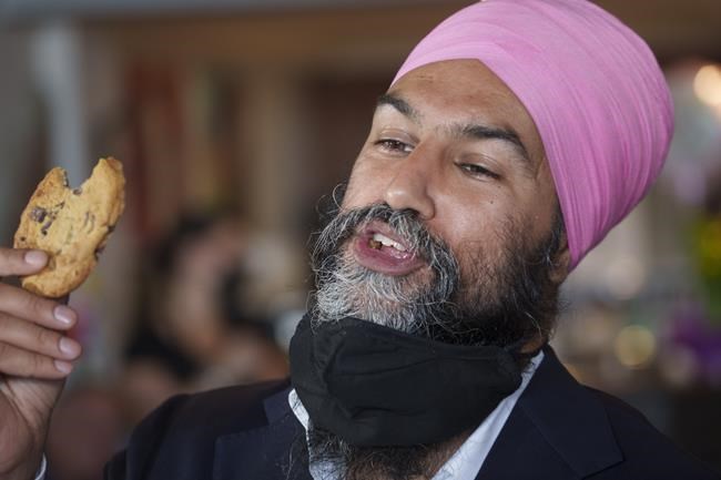 NDP Leader Jagmeet Singh reacts after tasting a homemade cookie during a campaign stop in a coffee shop in Brampton, Ont., Monday, Aug. 16, 2021. THE CANADIAN PRESS/Paul Chiasson