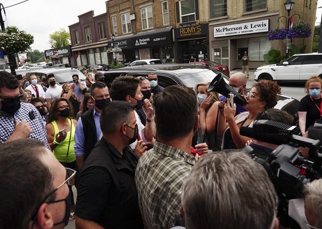 Liberal Leader Justin Trudeau is tightly boxed in as he reacts to being confronted by an anti-maskers and anti-vaxxers (holding megaphone) as he makes a whistle-stop in Aurora, Ont., on Tuesday, Aug. 17, 2021. THE CANADIAN PRESS/Sean Kilpatrick