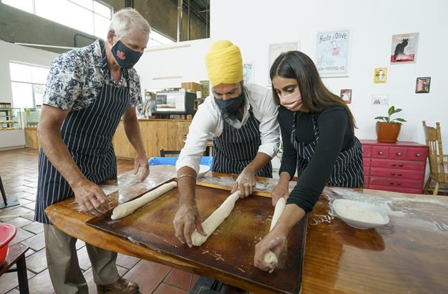 NDP Leader Jagmeet Singh and his wife Gurkiran Kaur Sidhu place the dough for a baguette on a pan after getting instructions from bakery owner Olivier Audibert in Coquitlam, B.C.,, on Tuesday, August 17, 2021. THE CANADIAN PRESS/Paul Chiasson