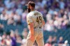 San Diego Padres starting pitcher Jake Arrieta holds the back of his left leg after giving up a solo home run to Colorado Rockies' Dom Nunez in the fourth inning of a baseball game Wednesday, Aug. 18, 2021, in Denver. Arrieta, who was making his first start for the Padres, was forced to leave the game. (AP Photo/David Zalubowski)