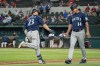 Seattle Mariners' Ty France (23) is congratulated by third base coach Manny Acta (14) after hitting a two-run home run off Texas Rangers relief pitcher Joe Barlow during the 11th inning of a baseball game Thursday, Aug. 19, 2021, in Arlington, Texas. Seattle won 9-8. (AP Photo/Jeffrey McWhorter)