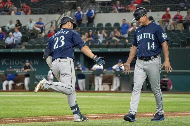 Seattle Mariners' Ty France (23) is congratulated by third base coach Manny Acta (14) after hitting a two-run home run off Texas Rangers relief pitcher Joe Barlow during the 11th inning of a baseball game Thursday, Aug. 19, 2021, in Arlington, Texas. Seattle won 9-8. (AP Photo/Jeffrey McWhorter)