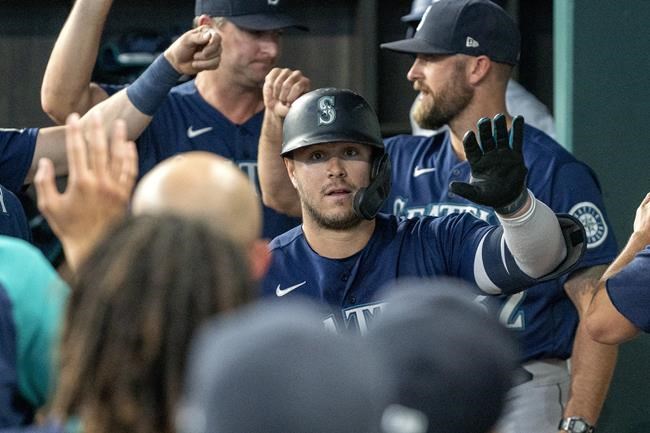 Seattle Mariners' Ty France (23) is congratulated in the dugout after hitting a two-run home run off of Texas Rangers relief pitcher Joe Barlow during the eleventh inning of a baseball game Thursday, Aug. 19, 2021, in Arlington, Texas. Seattle won 9-8. (AP Photo/Jeffrey McWhorter)