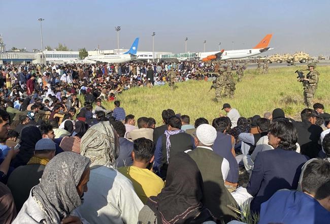 FILE - In this Monday, Aug. 16, 2021 file photo U.S. soldiers stand guard along the perimeter at the international airport in Kabul, Afghanistan. Hundreds of Western nationals and Afghan workers have been flown to safety since the Taliban reasserted control over the country. Yet still unprotected, and in hiding, are untold numbers of Afghans who tried to build a fledgling democracy. They include Afghans who worked with foreign forces, and who are now stranded and being hunted by the Taliban, along with aid workers.(AP Photo/Shekib Rahmani, File)