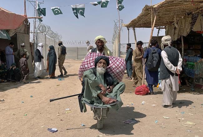 A porter pushes a wheelbarrow carrying an elderly Afghan man as he enters into Pakistan through a border crossing point, in Chaman, Pakistan, Friday, Aug. 20, 2021. Chaman, is a key border crossing between Pakistan and Afghanistan, normally thousands of Afghans and Pakistanis cross daily and a steady stream of trucks passes through, taking goods to Afghanistan. (AP Photo)