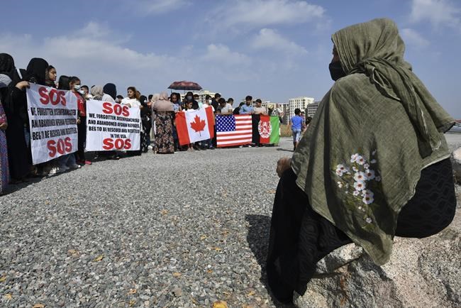 Afghans migrants take part in a rally outside the U.S. Embassy in Bishkek, Kyrgyzstan, Thursday, Aug. 19, 2021, requesting Kyrgyz citizenship or resettlement to the USA or Canada. (AP Photo/Vladimir Voronin)