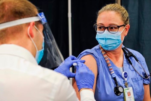 FILE - In this Dec. 16, 2020, file photo, Ingrid Radke, a critical care nurse in the ICU, receives the Pfizer-BioNTech COVID-19 vaccination at St. Peter's Health in Helena, Mont. Under a new law passed by the state's Republican-controlled Legislature earlier this year, requiring vaccines as a condition for employment is deemed 