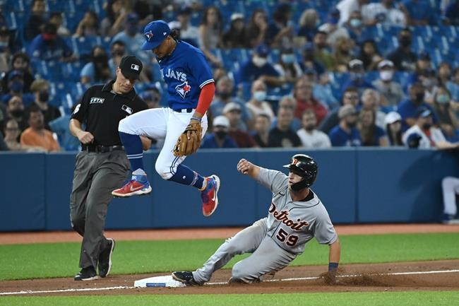 Detroit Tigers' Zack Short, 59, steals third base as Toronto Blue Jays' Santiago Espinal jumps clear in the eighth inning of an American League baseball game in Toronto on Friday, Aug. 20, 2021. THE CANADIAN PRESS/Jon Blacker
