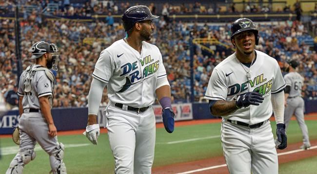 Tampa Bay Rays' Yandy Diaz, center, and Wander Cruz head for the dugout after scoring on an RBI-double hit by Brandon Lowe off Chicago White Sox starter Dallas Keuchel during the first inning of a baseball game, Saturday, Aug. 21, 2021, in St. Petersburg, Fla. (AP Photo/Steve Nesius)