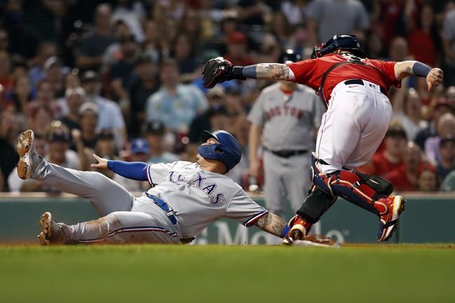 Texas Rangers' Yohel Pozo, left, beats a tag by Boston Red Sox's Christian Vazquez at home plate on a single by Brock Holt during the second inning of a baseball game, Saturday, Aug. 21, 2021, in Boston. (AP Photo/Michael Dwyer)