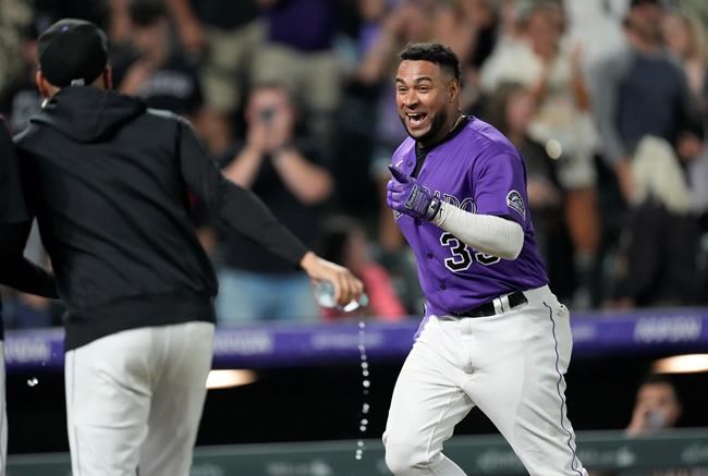 Teammates pursue Colorado Rockies' Elias Diaz, right, after his game-ending, three-run home run off Arizona Diamondbacks relief pitcher J.B. Wendelken during the ninth inning of a baseball game Saturday, Aug. 21, 2021, in Denver. The Rockies won 5-2. (AP Photo/David Zalubowski)