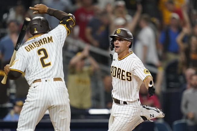 San Diego Padres' Adam Frazier, right, celebrates with Trent Grisham after scoring on a wild pitch during the 10th inning of the team's baseball game against the Philadelphia Phillies, Saturday, Aug. 21, 2021, in San Diego. (AP Photo/Gregory Bull)