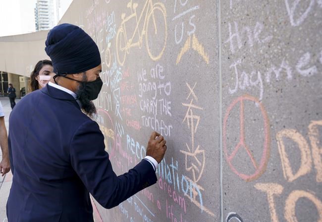 NDP leader Jagmeet Singh writes on a Jack Layton memorial wall to mark the tenth anniversary of the former NDP leader's death in Toronto , on Sunday, August 22, 2021. THE CANADIAN PRESS/Paul Chiasson