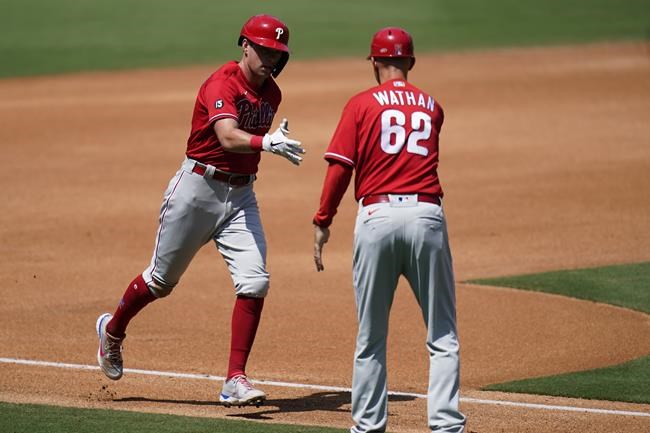 Philadelphia Phillies' Rhys Hoskins, left, is greeted by third base coach Dusty Wathan after hitting a home run during the fourth inning of a baseball game against the San Diego Padres, Sunday, Aug. 22, 2021, in San Diego. (AP Photo/Gregory Bull)