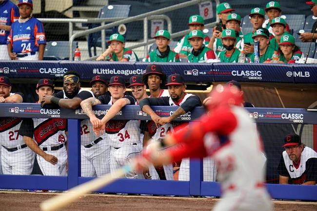 The Cleveland Indians dugout and the Little League team from Toms River, N.J., top right, watch as Los Angeles Angels' David Fletcher bats during the first inning of the Little League Classic baseball game at Bowman Stadium in Williamsport, Pa., Sunday, Aug. 22, 2021. (AP Photo/Gene J. Puskar)