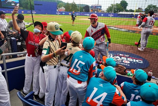 Los Angeles Angels' David Fletcher (22) poses for a selfie with a Little League team participating in the Little League World Series in attendance at the Little League Classic baseball game between the Cleveland Indians and the Los Angeles Angels at Bowman Stadium in Williamsport, Pa., Sunday, Aug. 22, 2021. (AP Photo/Gene J. Puskar)