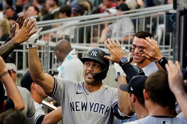 New York Yankees' Giancarlo Stanton, center, celebrates in the dugout after hitting a solo home run in the second inning of a baseball game Monday, Aug. 23, 2021, in Atlanta. (AP Photo/John Bazemore)