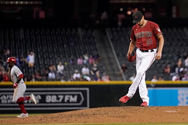 Arizona Diamondbacks relief pitcher Caleb Smith (31) kicks the dirt on the mound after giving up a home run to Philadelphia Phillies' Odubel Herrera, left, during the eighth inning of a baseball game Wednesday, Aug. 18, 2021, in Phoenix. The Diamondbacks won 4-2. (AP Photo/Ross D. Franklin)