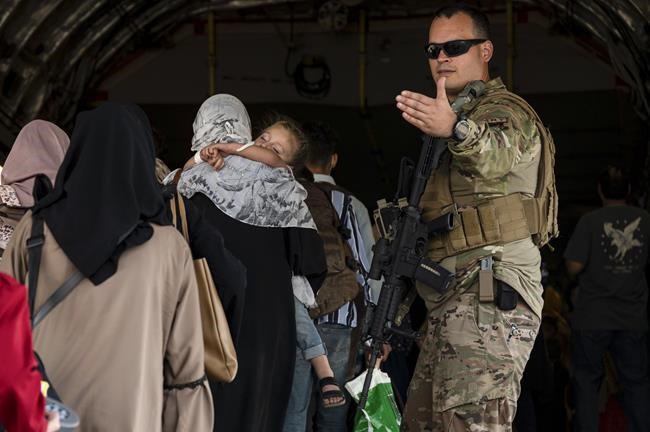 In this image provided by the U.S. Air Force, a U.S. Air Force Airman guides evacuees aboard a U.S. Air Force C-17 Globemaster III at Hamid Karzai International Airport in Kabul, Afghanistan, Tuesday, Aug. 24, 2021. (Senior Airman Taylor Crul/U.S. Air Force via AP)