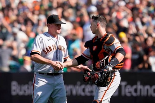 San Francisco Giants pitcher Jake McGee, left, celebrates with catcher Buster Posey after they defeated the Oakland Athletics in a baseball game in Oakland, Calif., Sunday, Aug. 22, 2021. (AP Photo/Jeff Chiu)