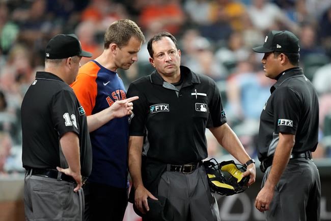 Home plate umpire Jim Reynolds, center right, is helped before leaving the field during the fifth inning of a baseball game between the Kansas City Royals and Houston Astros Tuesday, Aug. 24, 2021, in Houston. (AP Photo/David J. Phillip)