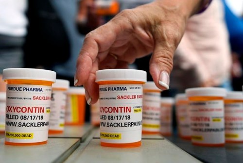 FILE - In this Aug. 17, 2018, file photo, family and friends who have lost loved ones to OxyContin and opioid overdoses leave pill bottles in protest outside the headquarters of Purdue Pharma in Stamford, Conn. A lawyer for the company, which is facing lawsuits over its marketing of the powerful painkiller OxyContin in driving the opioid epidemic, says states would get more money from settling rather than continuing their lawsuits against the Purdue Pharma and the Sackler family who own it. (AP Photo/Jessica Hill, File)