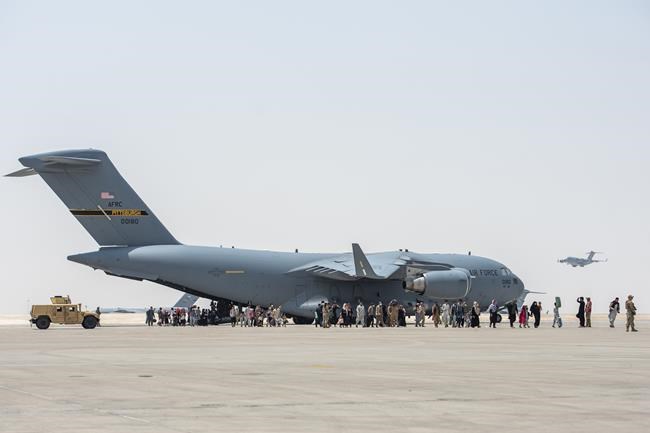 In this image provided by the U.S. Air Force, a C-17 Globemaster lll lands on the runway as evacuees from Afghanistan debark a C-17 Globemaster lll on Monday, Aug. 23, 2021, at Al Udeid Air Base, Qatar. (Airman 1st Class Kylie Barrow/U.S. Air Force via AP)